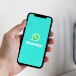 A hand holding a phone with the WhatsApp logo displayed | Photo by Anton from Pexels
