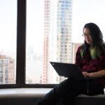 Woman using a laptop by the window | Photo by Christina Morillo