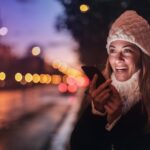 Cheerful woman recording voice message on smartphone in street | Photo by Andrea Piacquadio