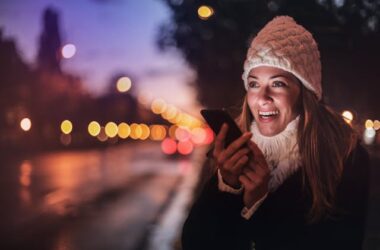 Cheerful woman recording voice message on smartphone in street | Photo by Andrea Piacquadio